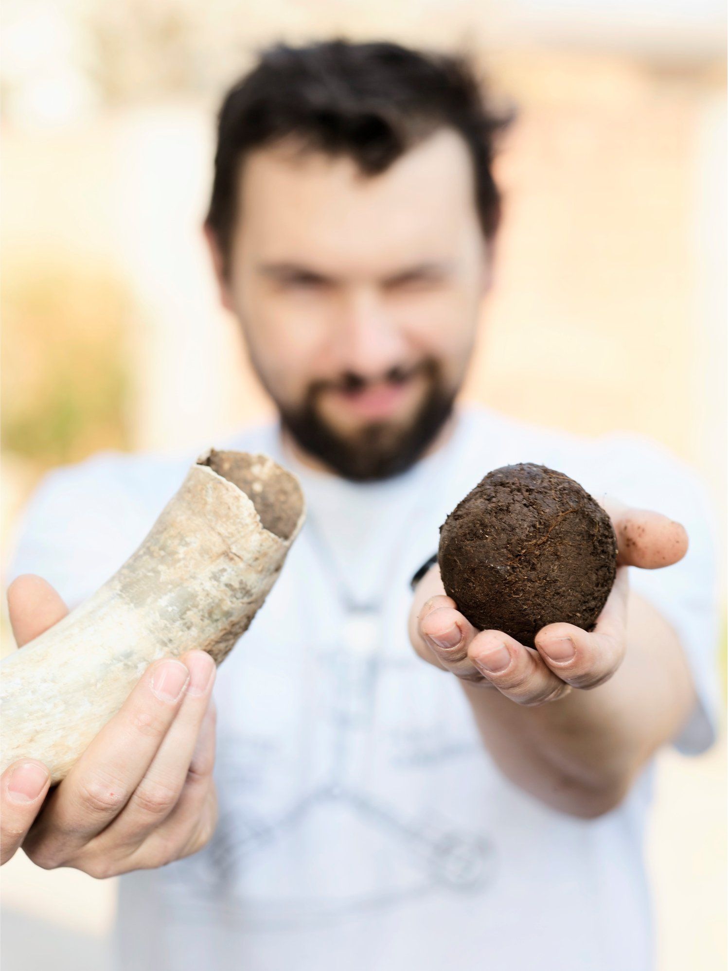 A Zillinger winemaker holds a cow horn and a ball of soil in his hands outdoors.