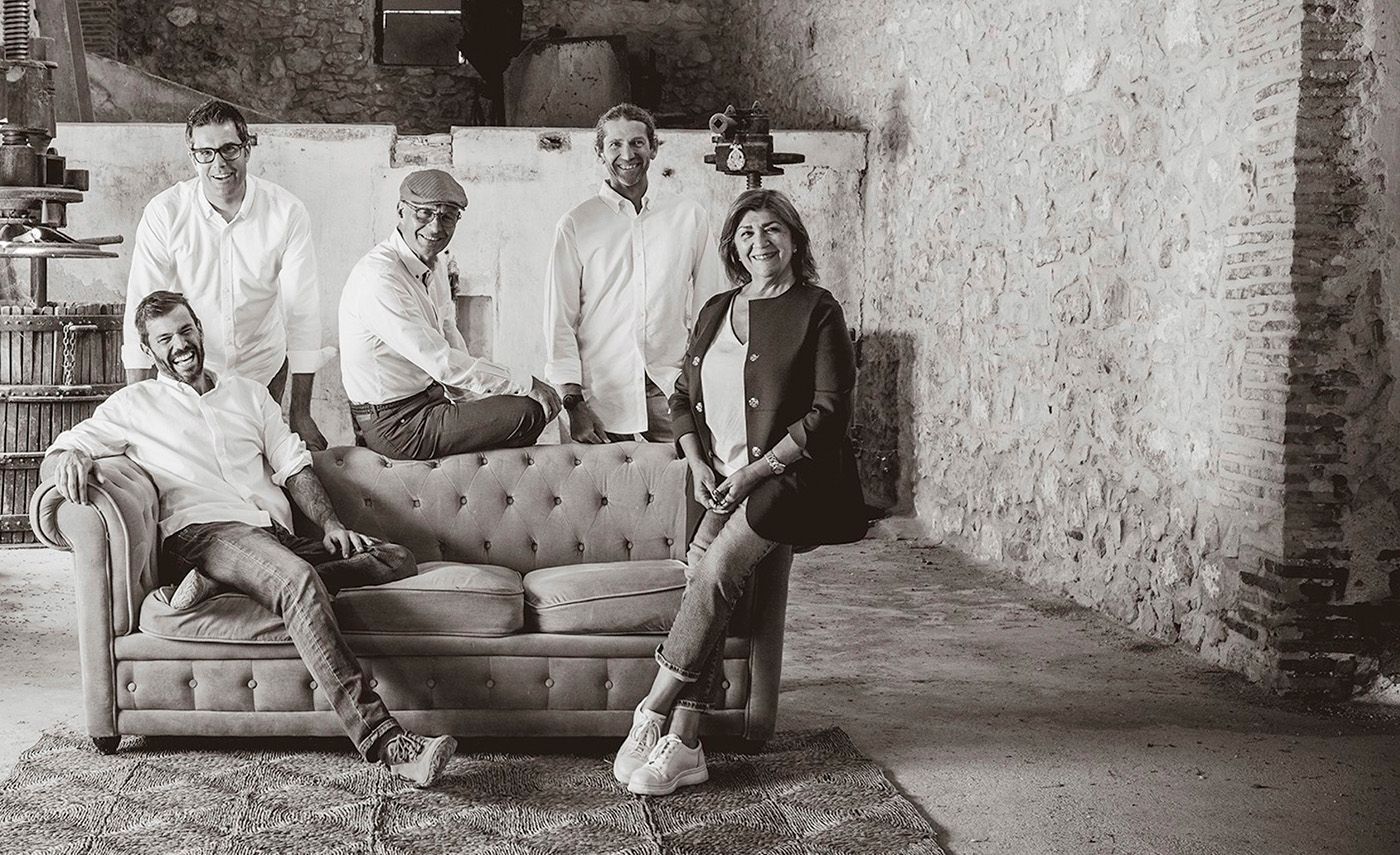 Group of six people posing in a rustic room, at Bodegas Enguera