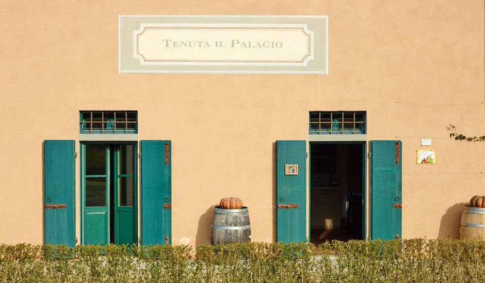 Peach-colored building with two green doorways, open shutters, and a sign that reads