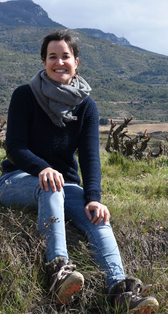 Woman sitting on a hillside, with mountain backdrop, at Sierra de Toloño.