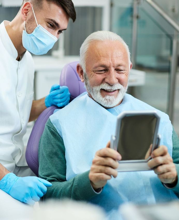 RESTORATIVE DENTISTRY | old man smiling in mirror at dental office | Veneers, implants, dentures