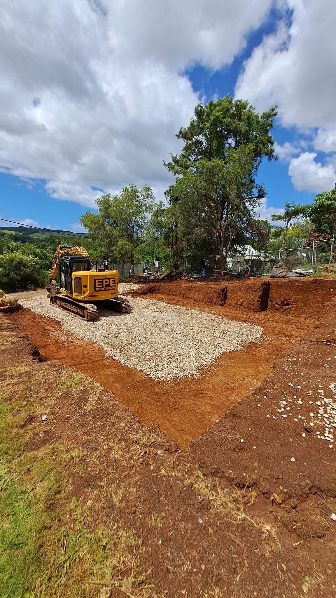 A Yellow Digger Sits On A Pile Of Gravel — East Point Earthmoving in Byron Bay, NSW