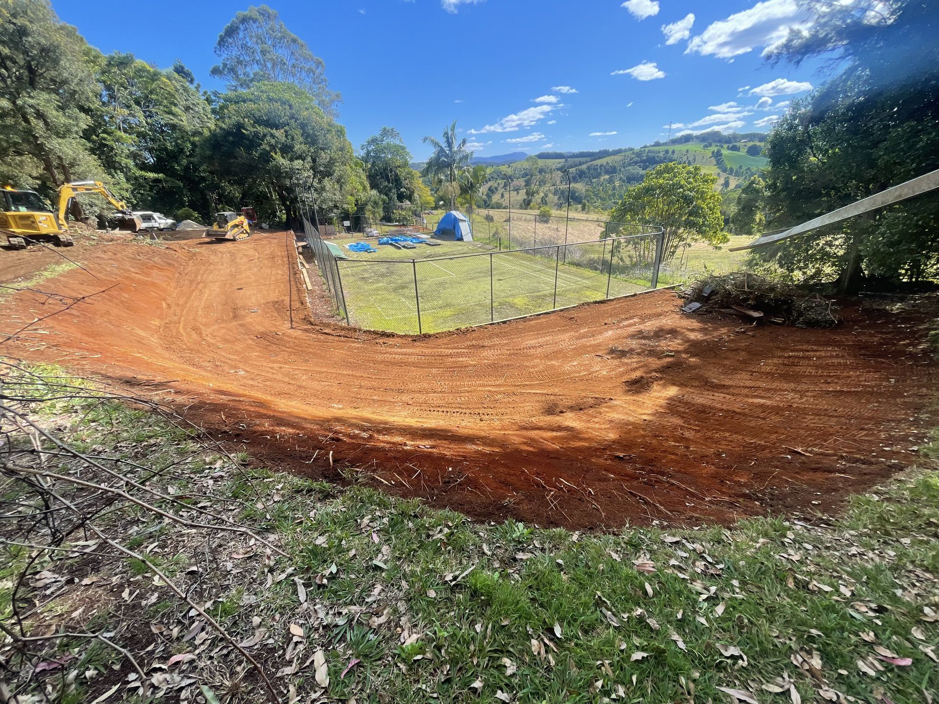 A Large Yellow Excavator Is Sitting On Top Of A Dirt Field — East Point Earthmoving in Byron Bay, NSW