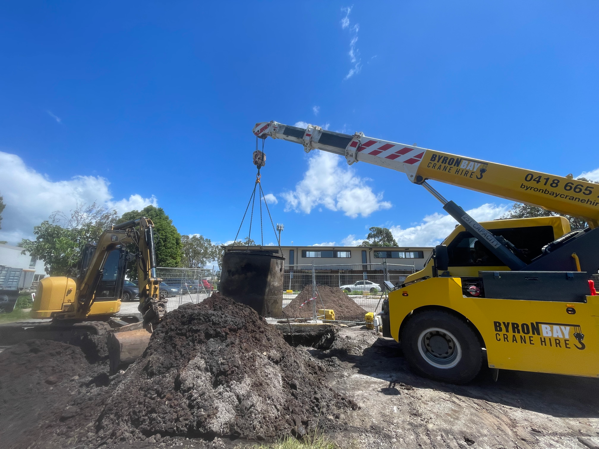 A Yellow Crane is Lifting a Large Pile of Dirt — East Point Earthmoving in Byron Bay, NSW