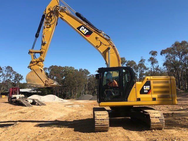 A Yellow Cat Excavator Is Sitting In The Dirt On A Construction Site — East Point Earthmoving in Byron Bay, NSW