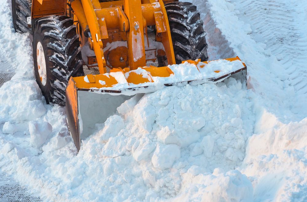 A yellow snow plow is clearing snow from a road.