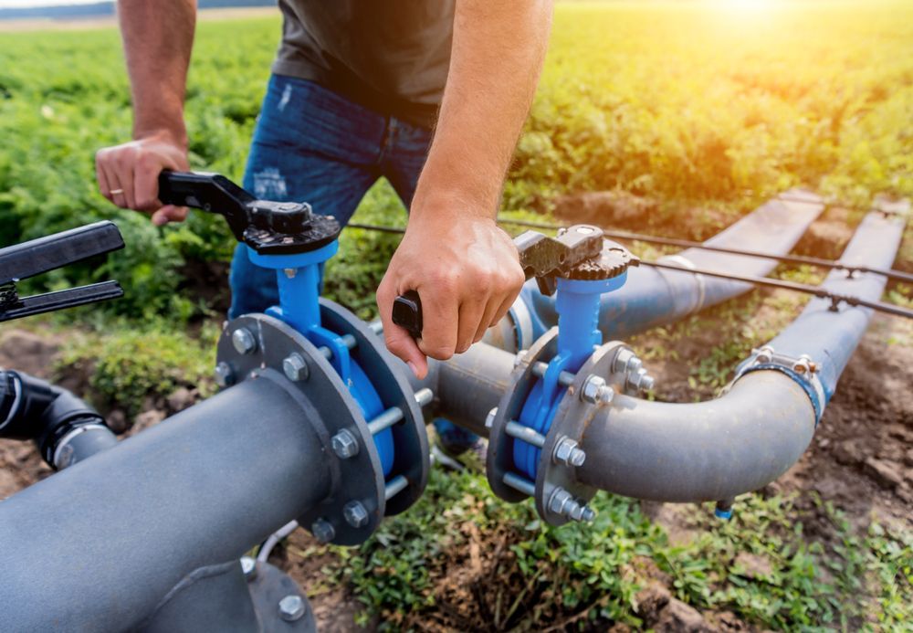 A man is working on a water pipe in a field.