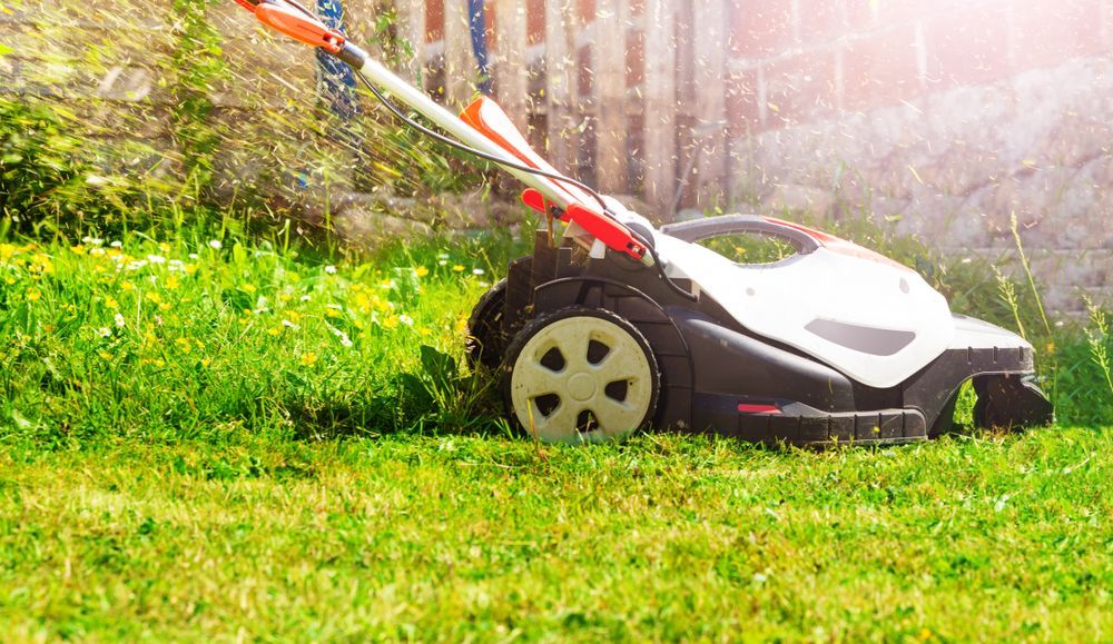 A person is mowing a lush green lawn with a lawn mower.