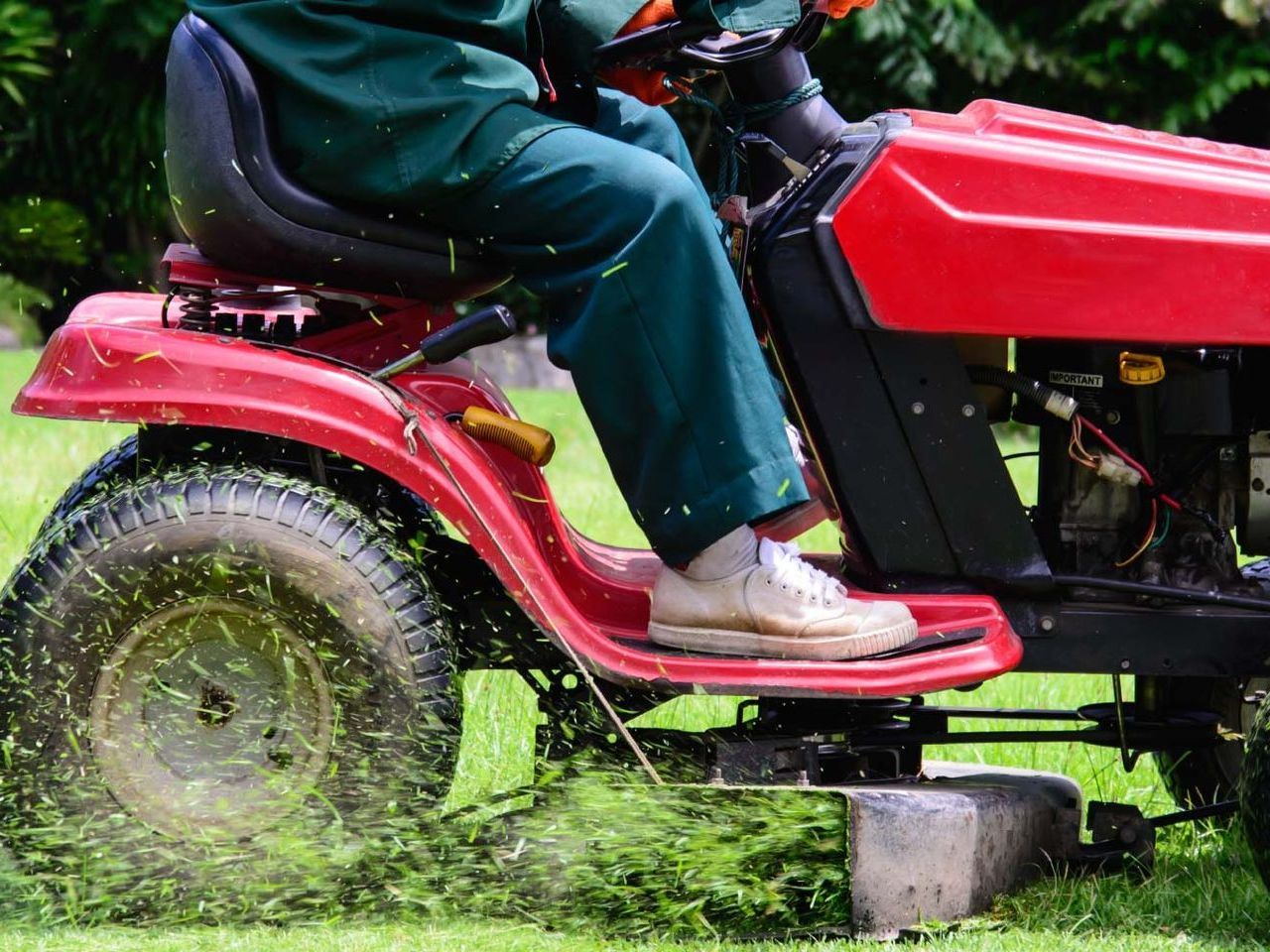 A person is riding a lawn mower on a lush green lawn.