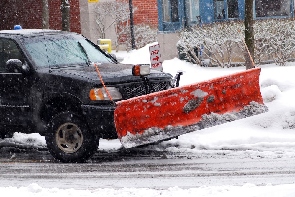 A black truck with a red snow plow on the side of it