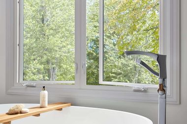 A close-up view of an open white window, highlighting the metal scissor-hinge mechanism attached to the frame.