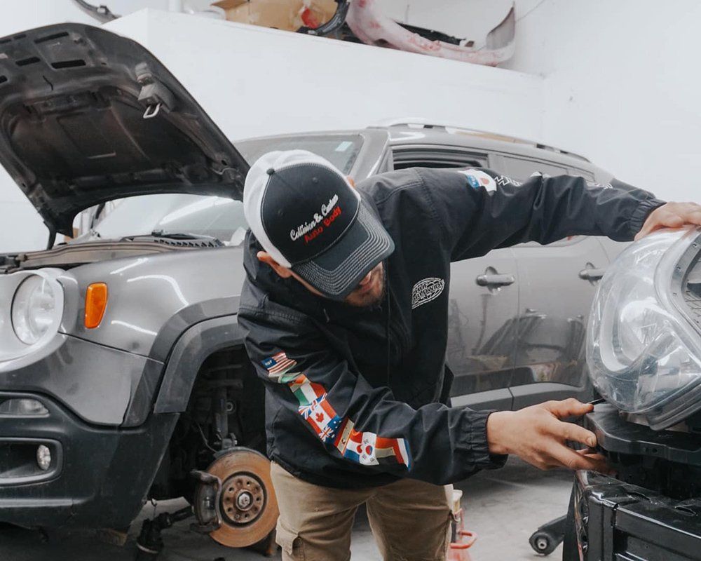 A man is working on the headlight of a car in a garage.