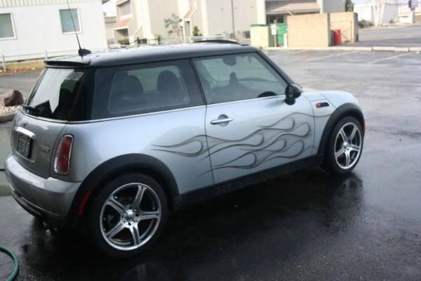 A silver mini cooper with flames painted on the side