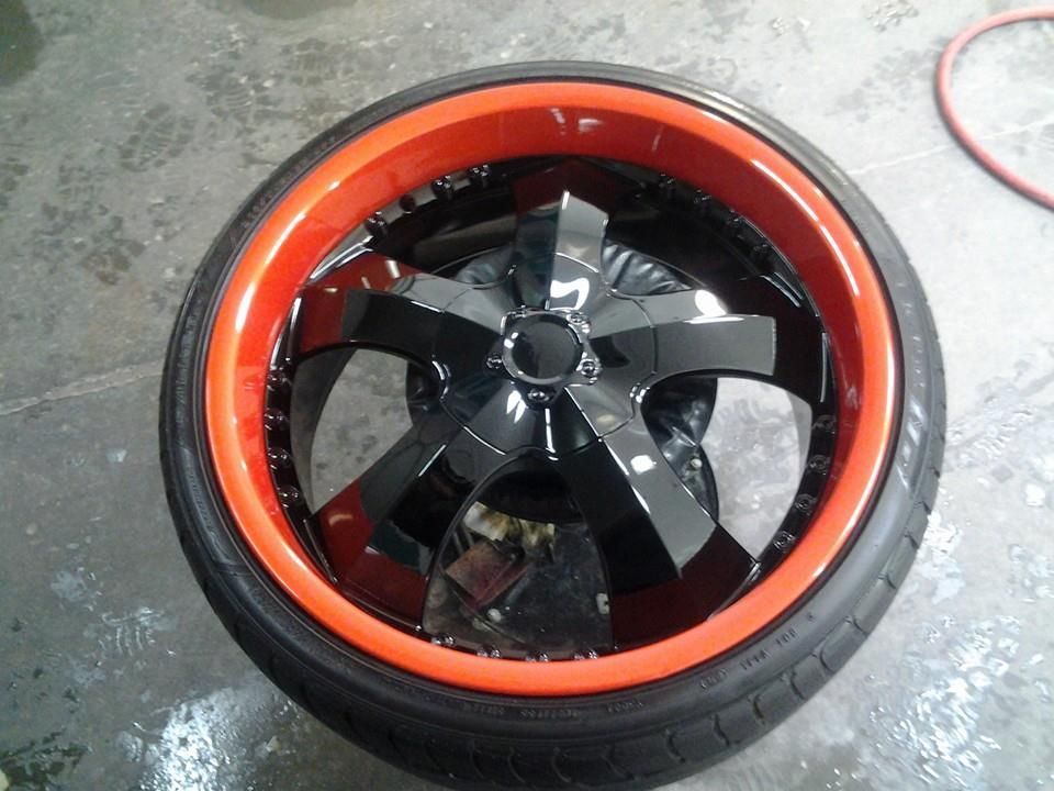 A black wheel with red rims and a black tire