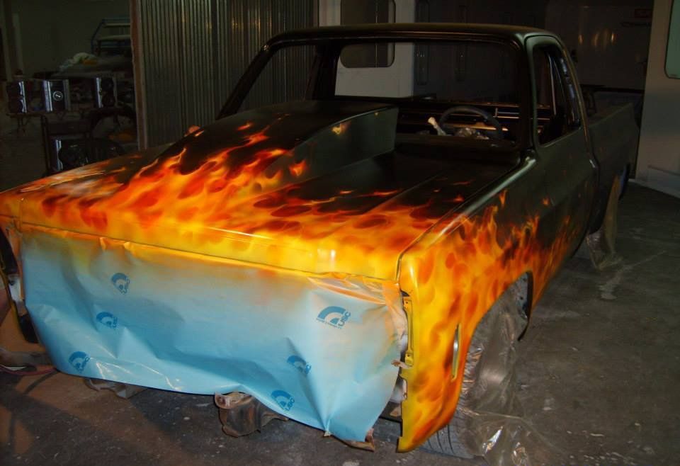 A truck with flames painted on it is sitting in a garage.