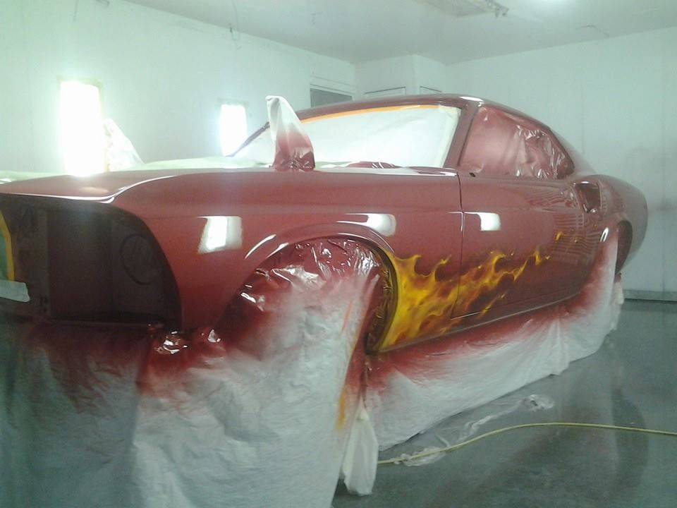 A red car is being painted in a garage
