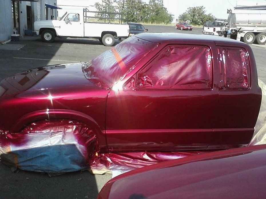 A red truck is being painted in a parking lot