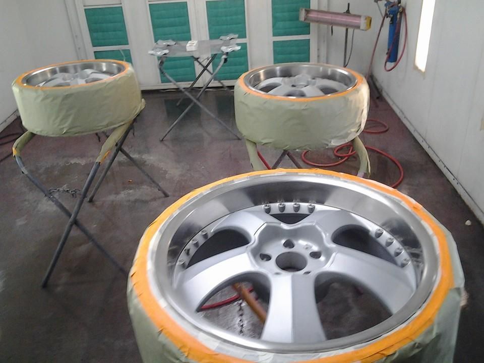 Three wheels are being painted in a paint booth