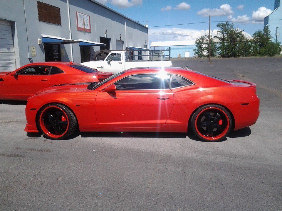 Two red cars are parked in front of a building