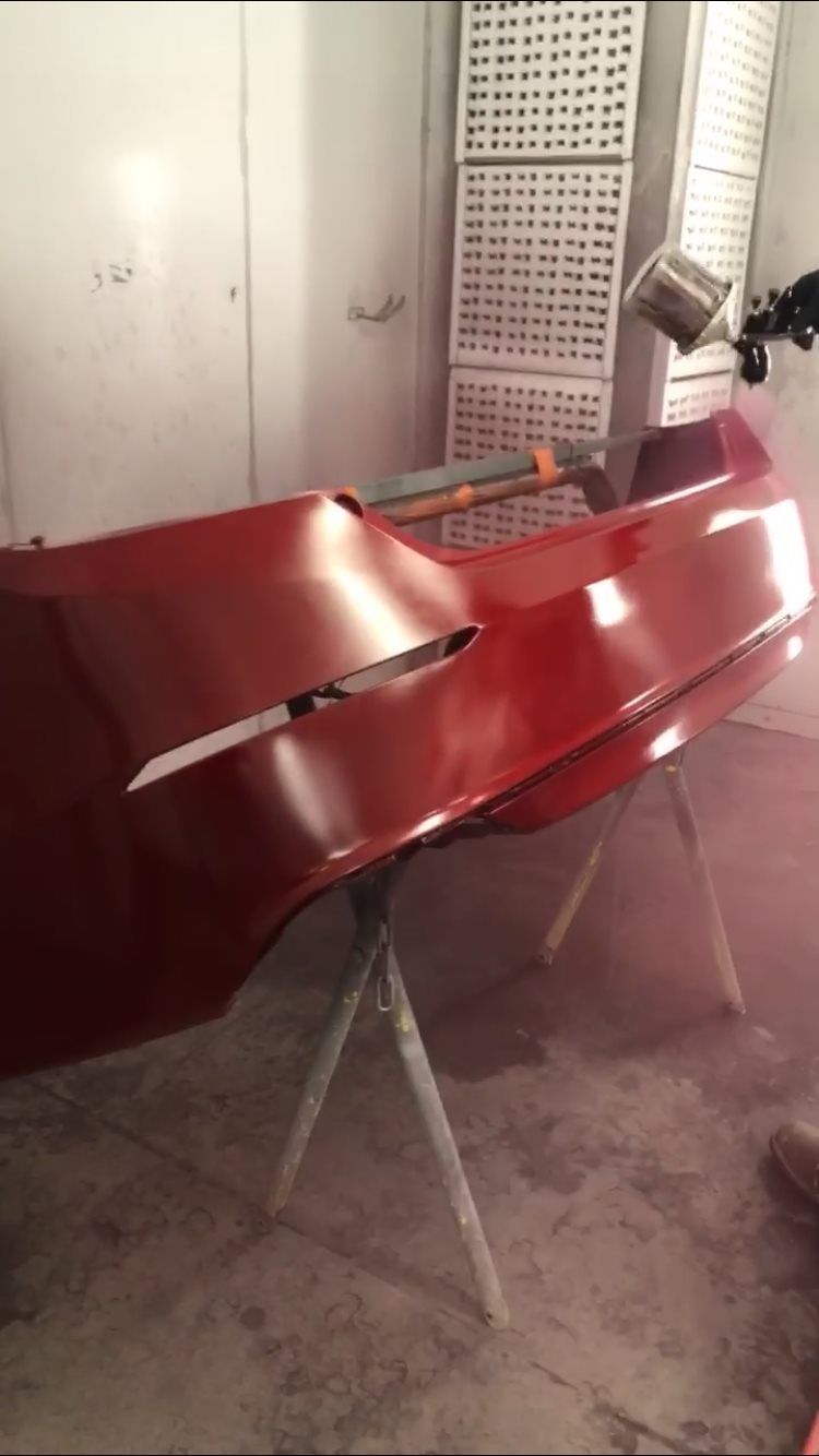 A red car is being painted in a garage