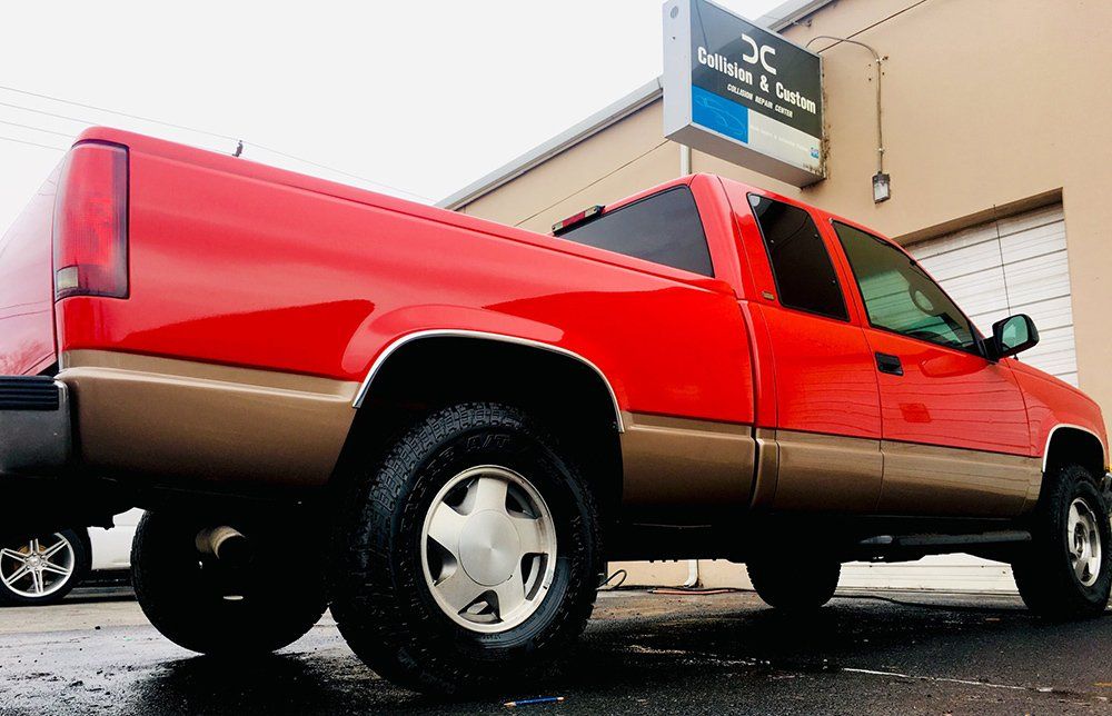 A red truck is parked in front of a building.