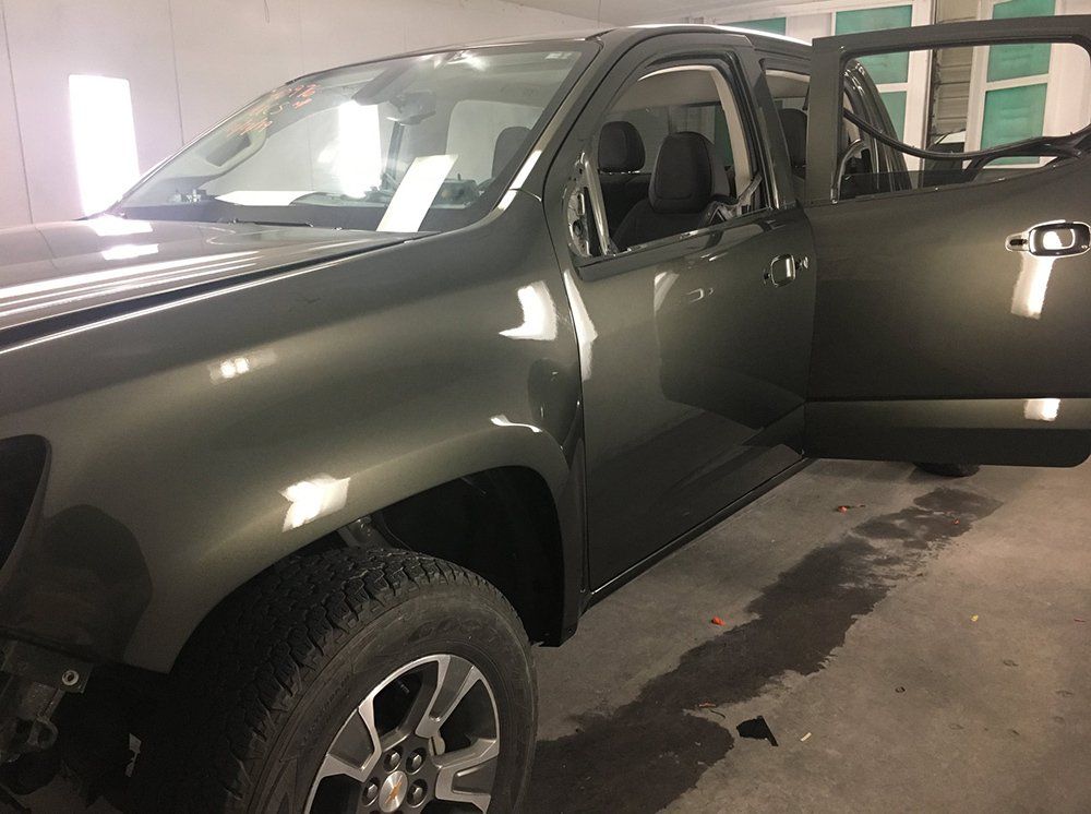 A truck is parked in a garage with its doors open.