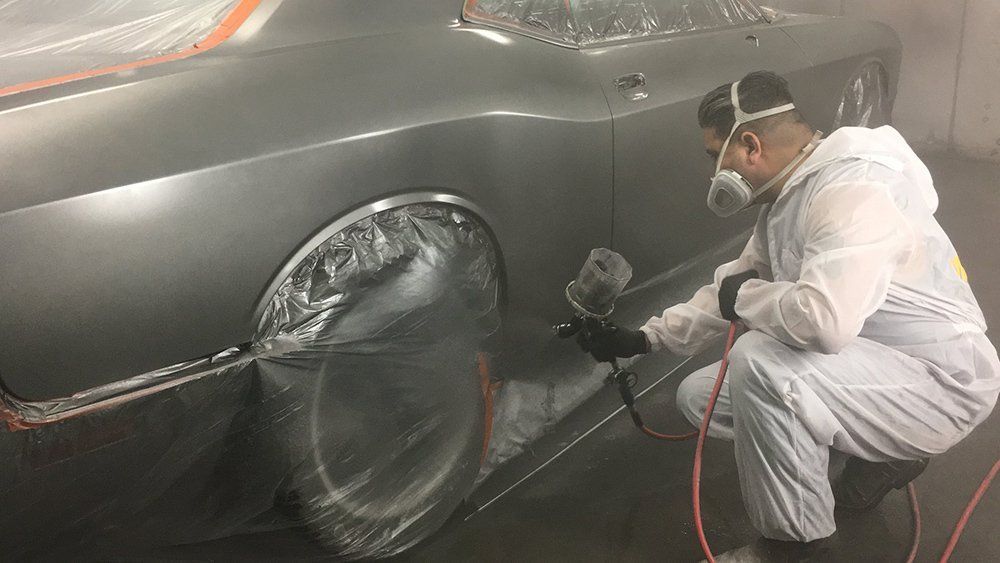 A man is spray painting a car in a garage.