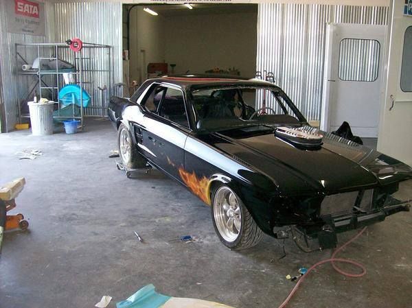 A black car with flames painted on the side is in a garage