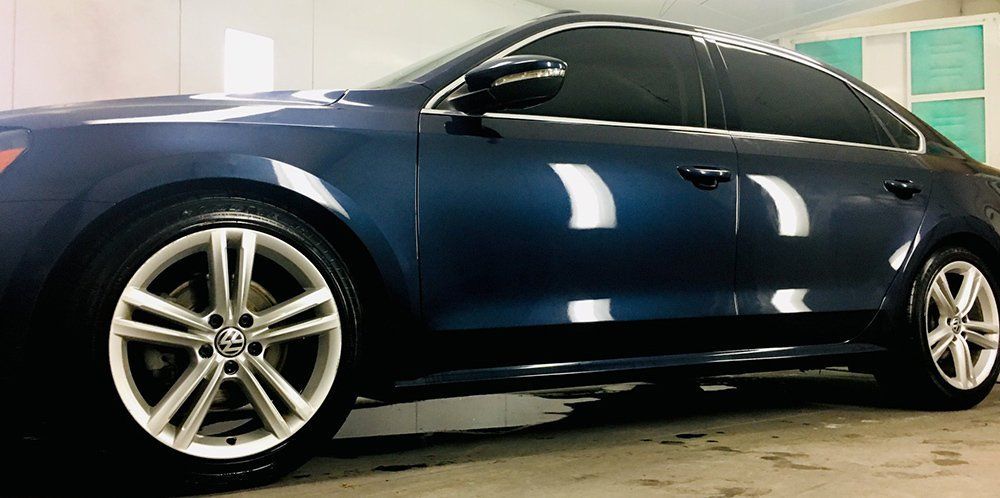 A blue car with silver wheels is parked in a garage.