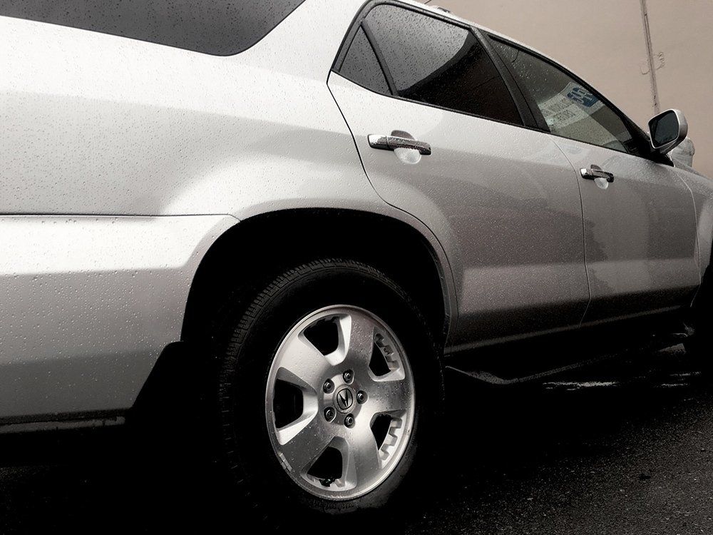 A silver car is parked in front of a building