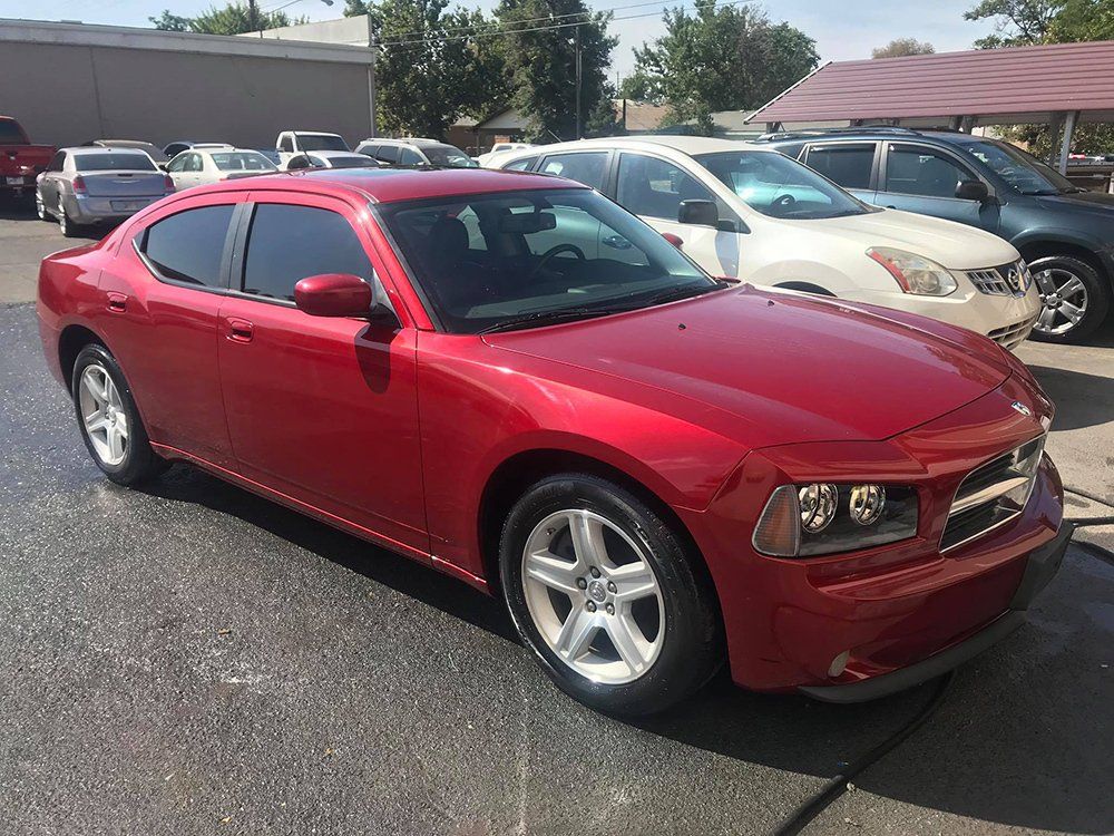 A red dodge charger is parked in a parking lot.