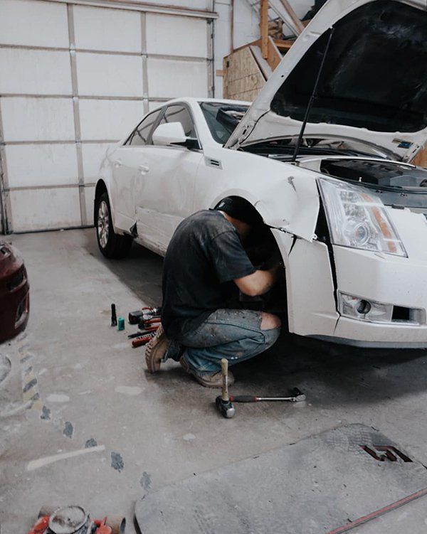 A man is working on a white car in a garage.