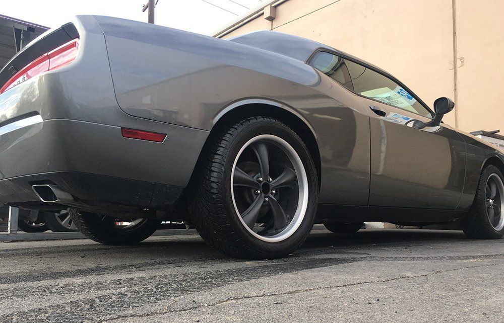 A gray dodge challenger is parked in front of a building.