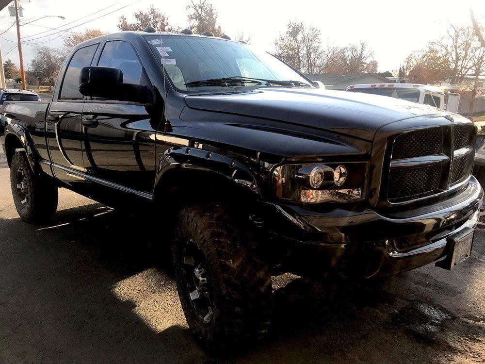 A black dodge ram truck is parked on the side of the road.