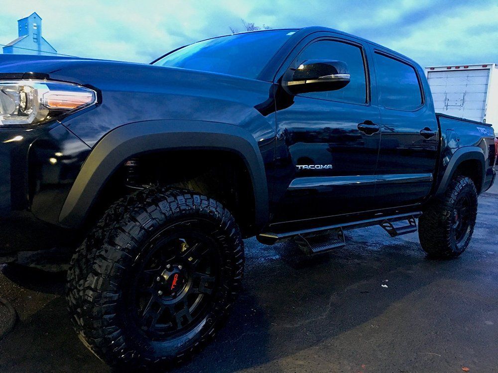 A black tacoma truck is parked in a parking lot