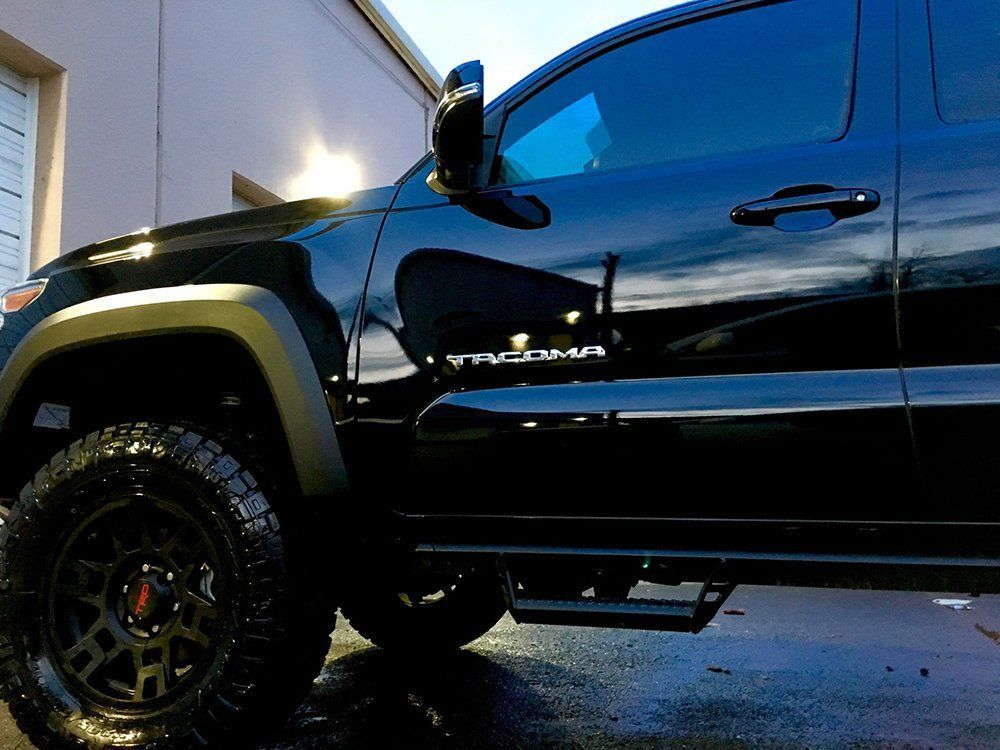 A black tacoma truck is parked in front of a building