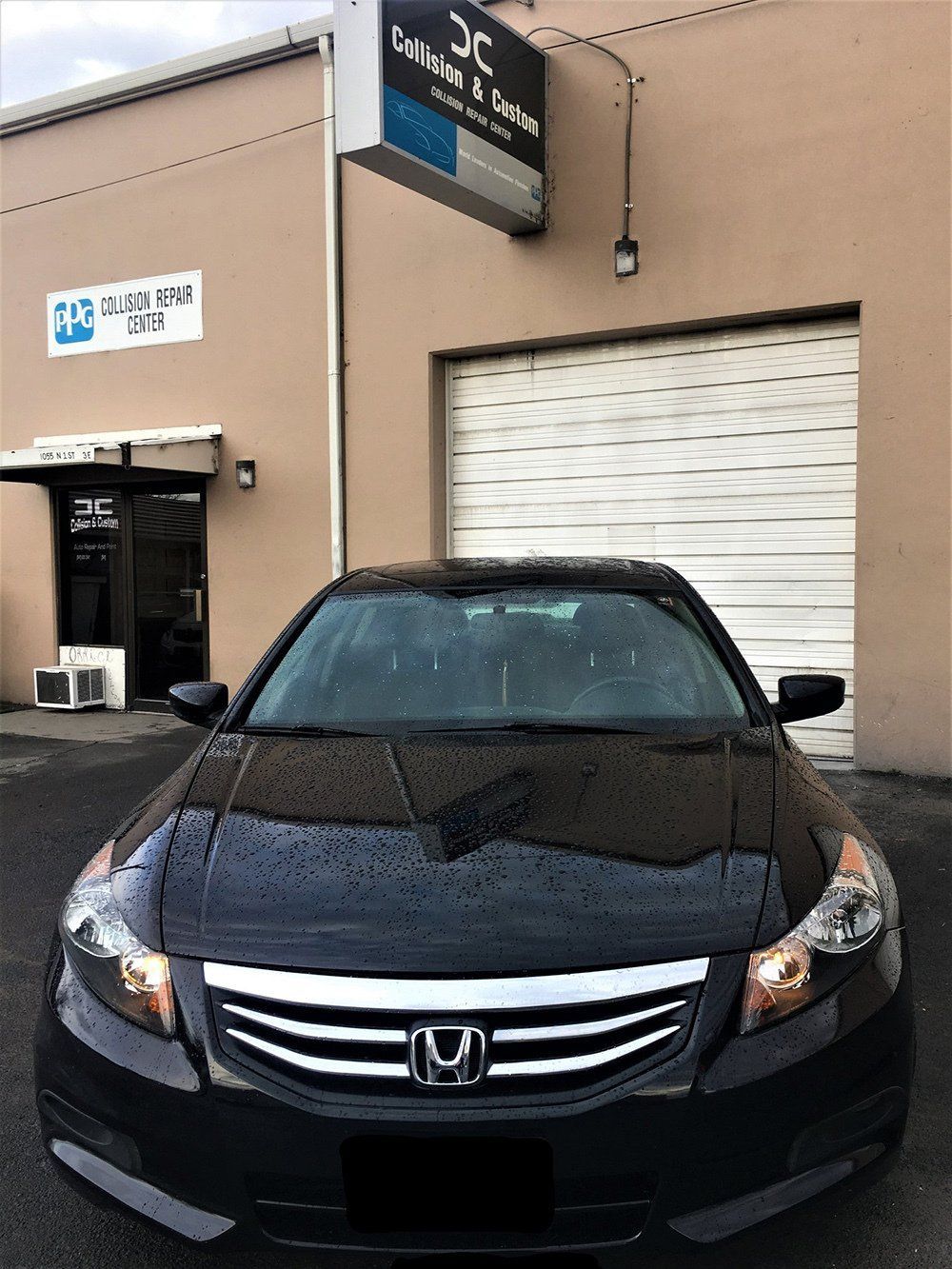 A black honda accord is parked in front of a building.