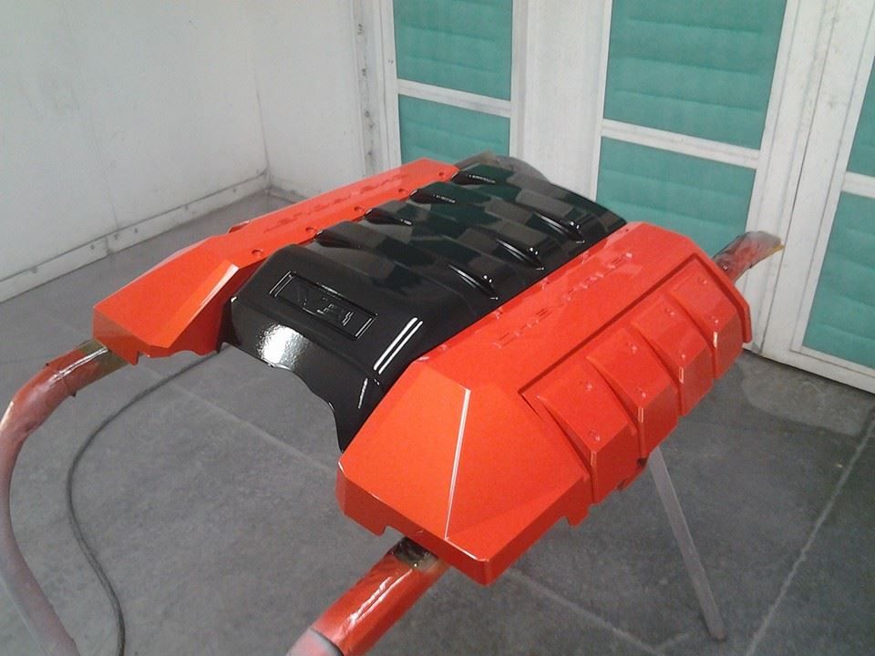 A black and orange engine cover is sitting on a stand