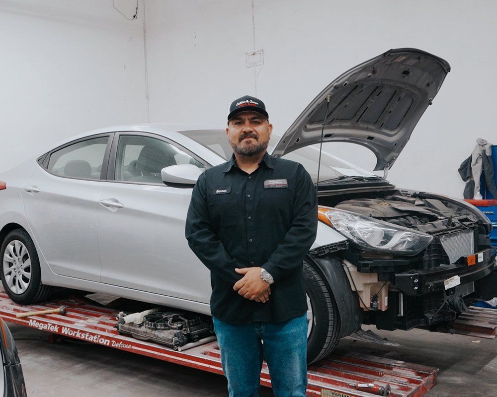 A man is standing in front of a car with the hood up.