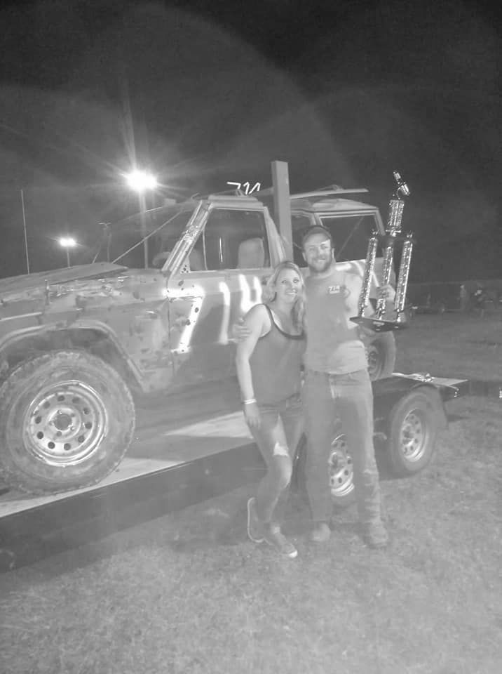 A man and a woman are posing for a picture in front of a truck.