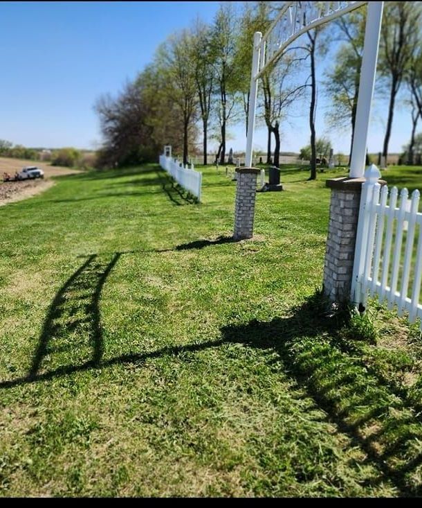 A white picket fence surrounds a lush green field.