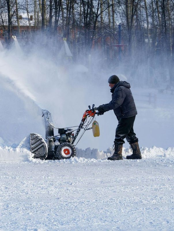 A man is using a snow blower to clear snow from the ground.