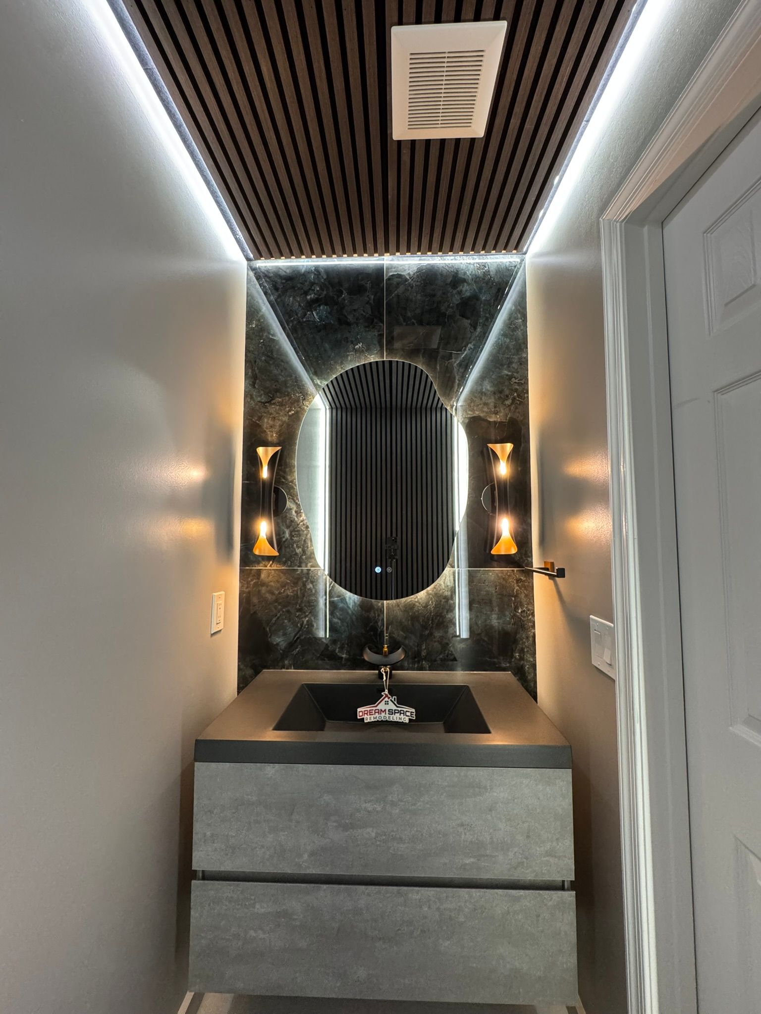 Bathroom remodeling Reisterstown, MD with modern powder room design featuring smart toilet, floating vanity, and black & gold faucet with LED lighting