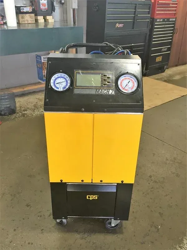 Yellow and black wheeled service machine with gauges and a display in a workshop.