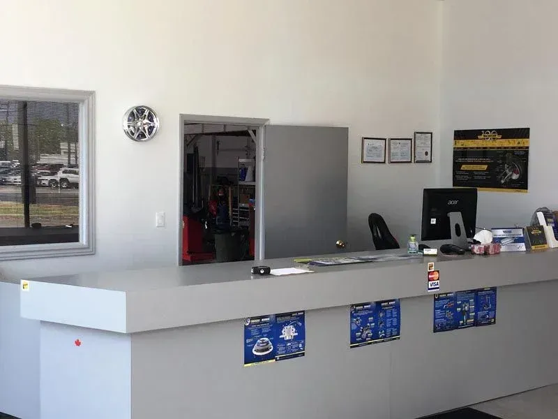 Empty service counter in a small office lobby with windows, a desk, and open back room.
