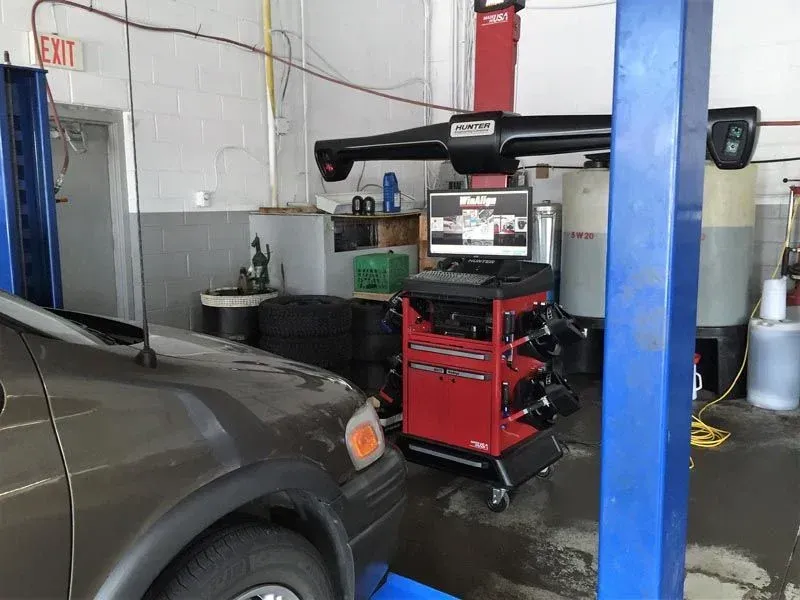 Auto shop with a gray SUV on a lift and red tire service equipment in the center.