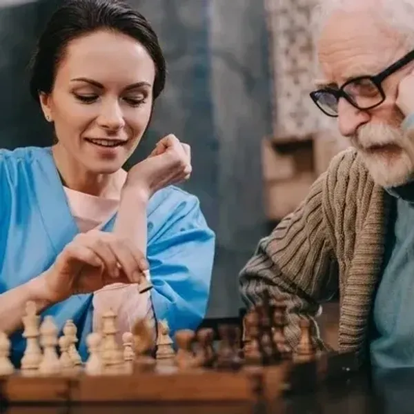 Caregiver providing companion care playing chess