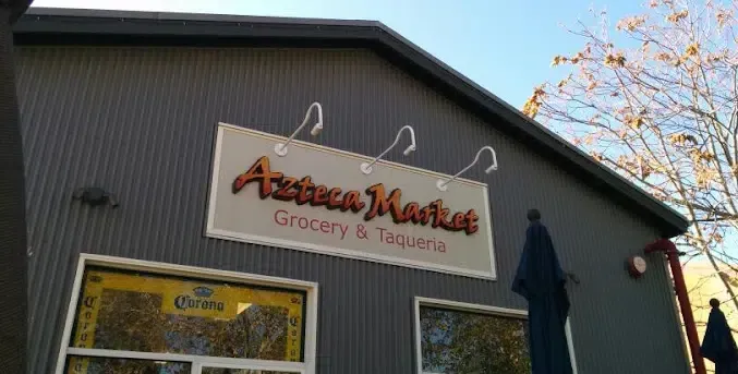A store front with a sign that says azteca market grocery & taquitos