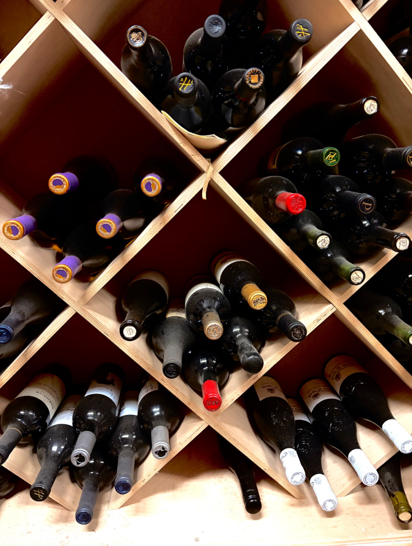 Wine bottles stored horizontally in a wooden home wine cellar rack, proper aging position for long-term cellaring.