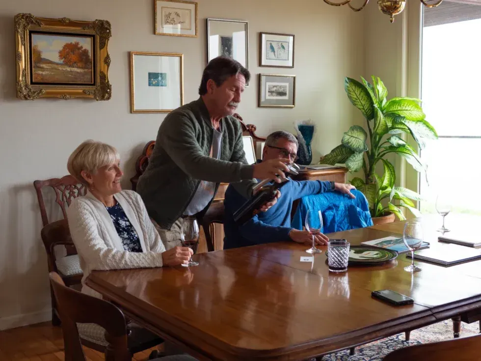 A man is pouring a bottle of wine into a woman 's glass